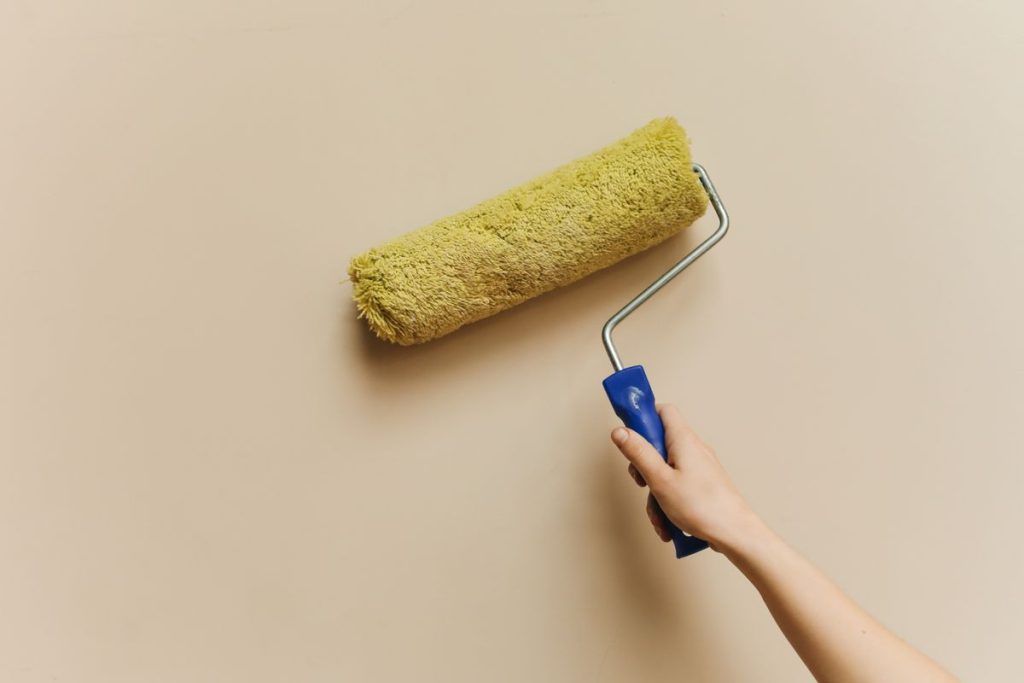 Hand rollt Wandfarbe auf eine Innenwand auf